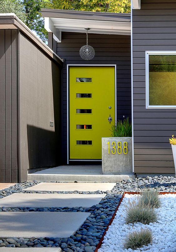 A mid century modenr neon green front door with glass pants and a concrete planter with a neon green house number for a modern home