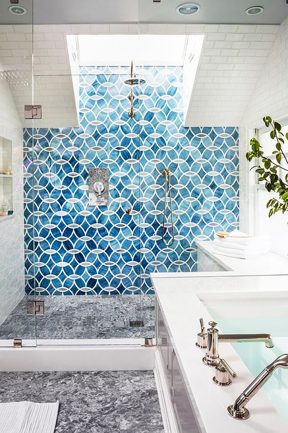 a modern and elegant bathroom with blue tiles in the shower and a skylight brightens up the shower space and makes it more inviting