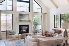 a modern farmhouse living room in neutrals, with black framed French windows, a built-in fireplace, neutral furniture and a wooden console table