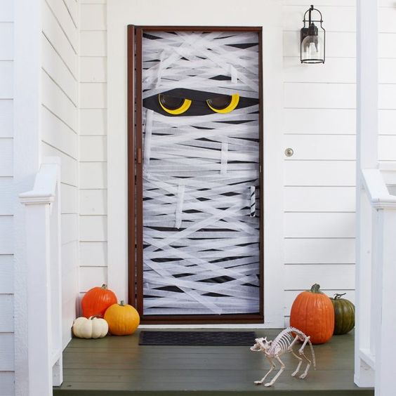 A mummy shaped front door, a couple of pumpkins and a cat skeleton are all you need to make your front porch look Halloween like
