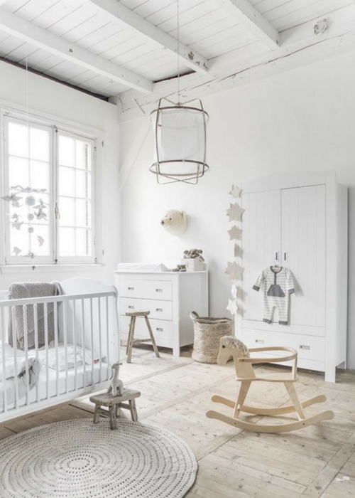 a pure white Scandinavian nursery with a dresser, a wardrobe, a crib, some stools and a pendant lamp plus pretty and cute decor