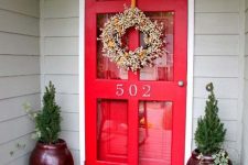 a red glass front door plus an additional red door inside and burgundy planters with greenery for a super bright entrance to the house