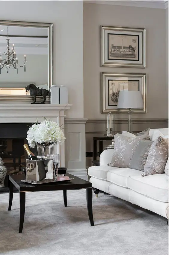 a refined neutral living room with greige paneling, a built-in fireplace, a white sofa, a black coffee table and an elegant gallery wall