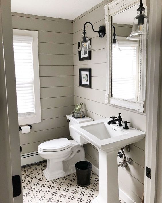 a rustic greige bathroom with planked walls and tiles on the floor, a free-standing sink and white appliances, a vintage mirror and sconces