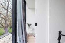 a small and delicate white pocket door with a black handle is a cool idea to hide a bathroom in a bedroom and looks cool