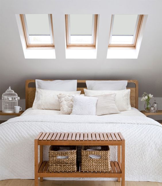 a small attic space with three skylights instead of a headboard is a nice idea to get natural light and visually enlarge the space