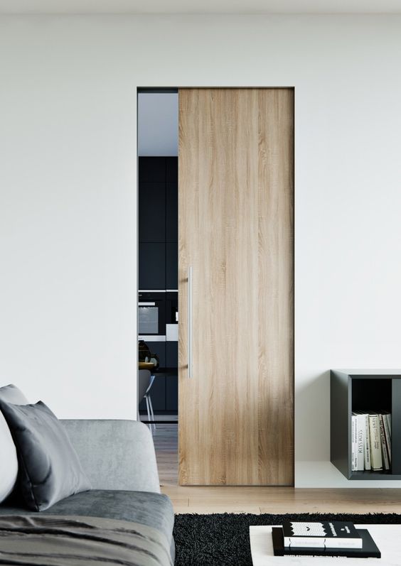 A small light stained pocket door with sleek and long handle is a stylish way to separate the spaces ina  contemporary home