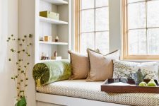 a small windowsill reading nook with bright pillows and built-in shelves looks super cozy and fresh and welcomes you to read
