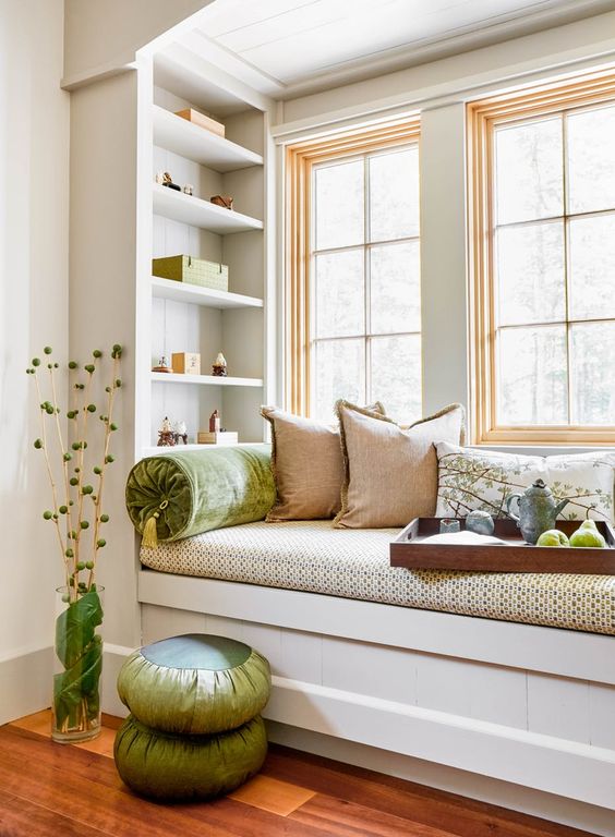 A small windowsill reading nook with bright pillows and built in shelves looks super cozy and fresh and welcomes you to read