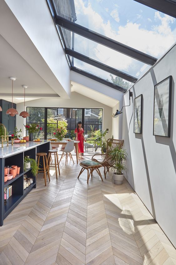a stylish and chic space with a kitchen and a dining room, with a glazed wall and a series of skylights that cozy up the space