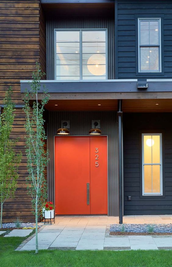 A stylish modern orange metal front door with a house number is an ultimate solution for a mid century modern house