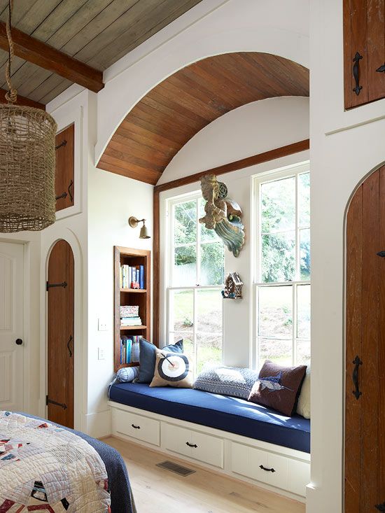 A traditional windowsill reading space with an upholstered bench with drawers and built in stained bookshelves