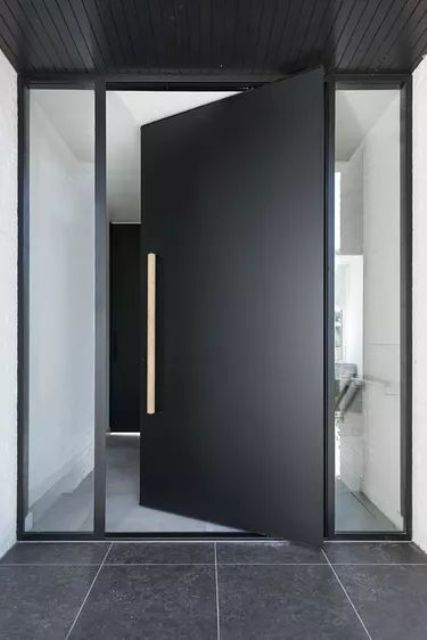 a very laconic and stylish matte black metal front door with a handle and long and narrow windows on each side is amazing