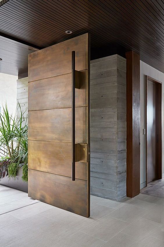 a weathered oversized metal front door with an oversized handle is a cool idea for a modern house and it makes a statement