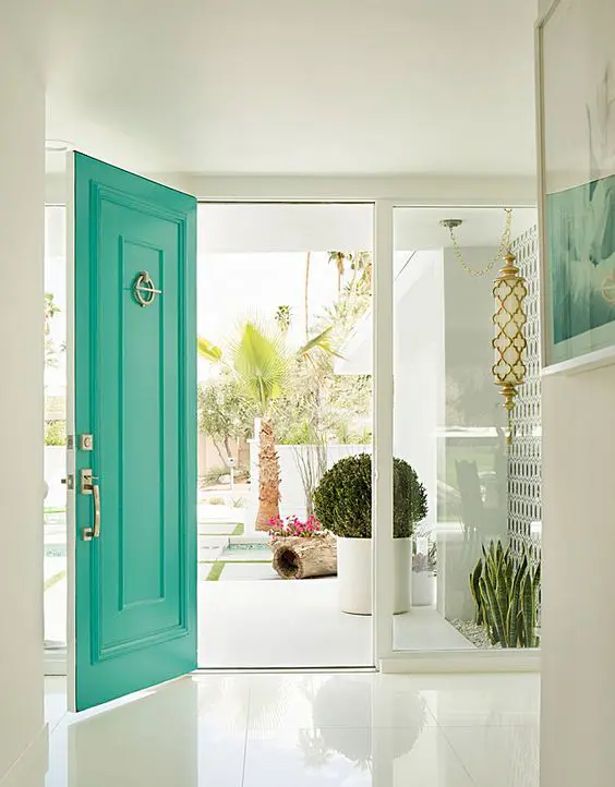 A white entrance accented with a bold green front door and gold touches are perfect for a mid century modern house