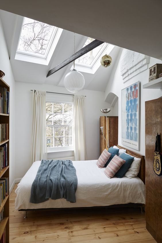 additional skylights add more natural light to this small bedroom and make it look bigger, and pendant lamps highlight the tall ceiling