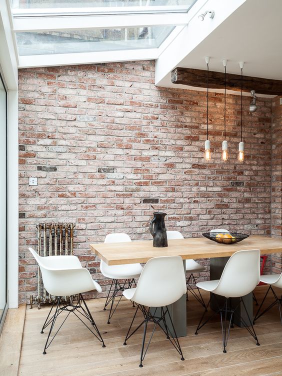 an industrial dining space with skylights is filled with daylight and pendant lamps highlight the high ceiling