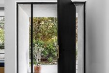 an oversized black metal front door with long and narrow windows on each side is a gorgeous solution for both a modern and a contemporary home