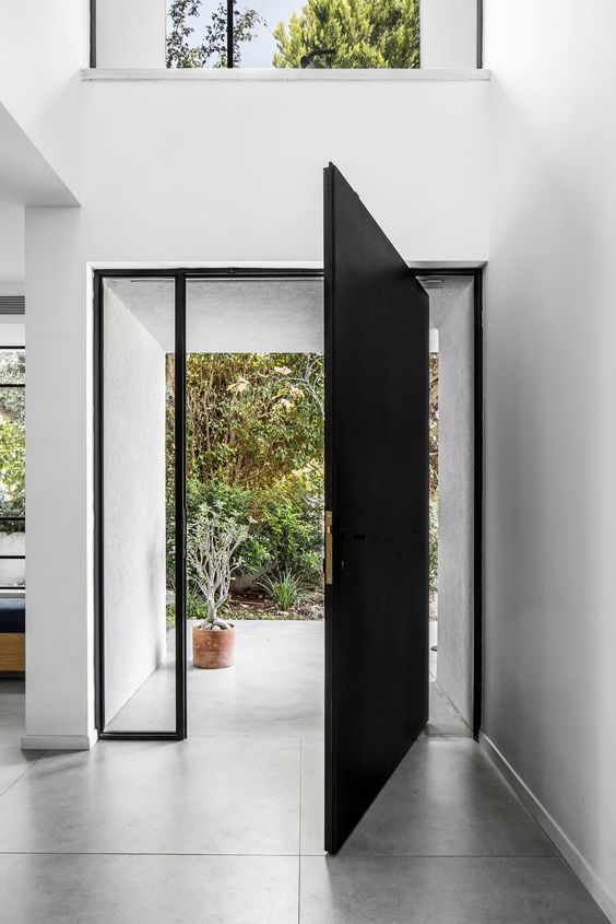 an oversized black metal front door with long and narrow windows on each side is a gorgeous solution for both a modern and a contemporary home