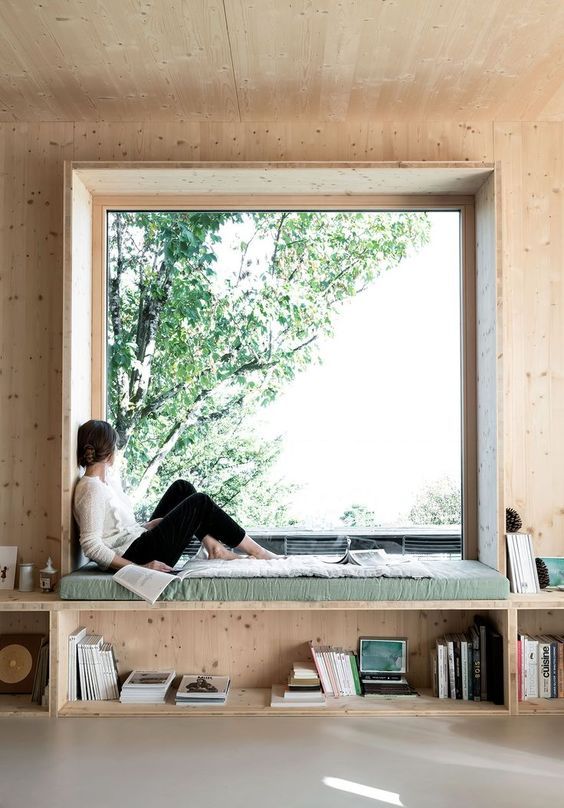 an oversized window with a built-in daybed and open shelves under it is a dreamy space to read, study and just sit and dream