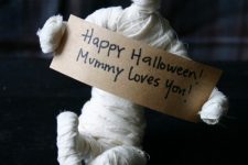 fun tabletop mummy decor with a sign is a cool idea to DIY for the coming Halloween to add a bit of fun