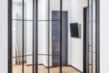 spaces separate with black metal frame and glass folding doors have more light in and such doors look more stylish and cool