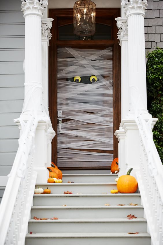 such a mummy-style front door is very easy to make, add a couple of pumpkins and fall leaves on the steps and voila - you have a Halloween porch