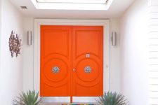super bright orange front doors with refined vintage knobs are a great example of chic mid-century modern decor style to go for