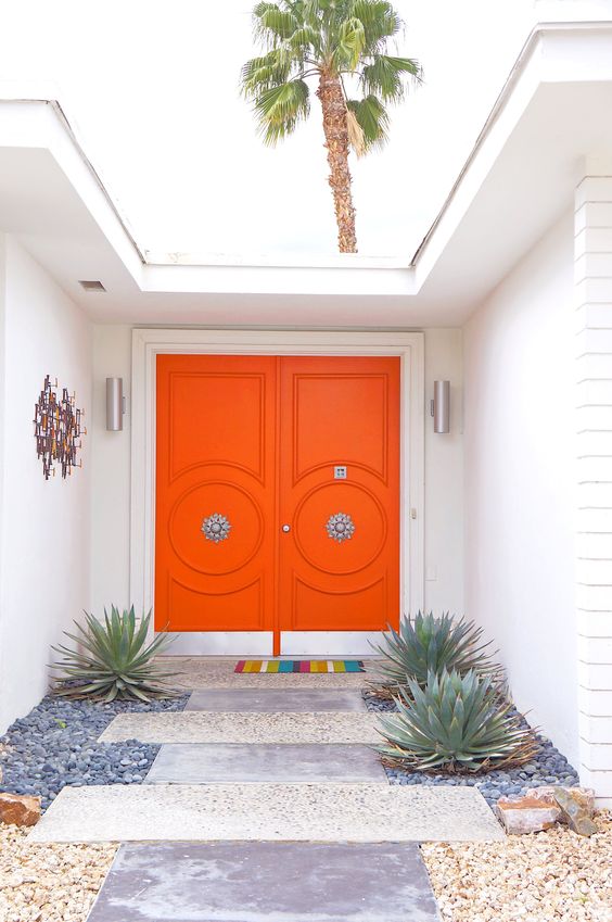 super bright orange front doors with refined vintage knobs are a great example of chic mid-century modern decor style to go for