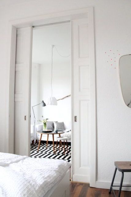 vintage-inspired white pocket doors separate the bedroom from the living room without wasting any space at all