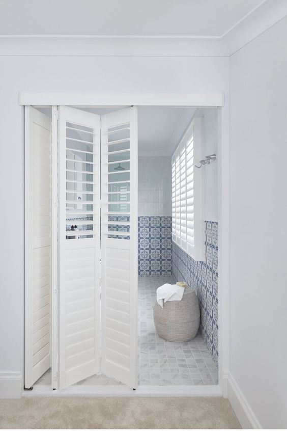 White shutter folding doors leading to the en suite bathroom are enough to separate it from the bedroom and don't divide the space too much