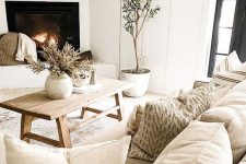 05 a neutral living room with super natural decor, a mantel, potted plants, a wooden coffee table and lots of pretty pillows