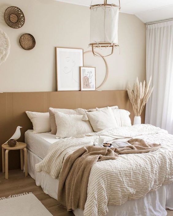 a dreamy boho lux bedroom in neutrals, with a bed with an extended headboard, a pendant lamp, woven baskets and neutral bedding
