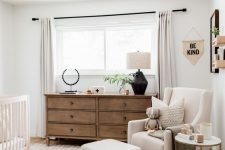 10 a mid-century modern neutral nursery with a white crib, a neutral chair with a footrest, a stained dresser and neutral textiles is welcoming