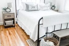 28 a dreamy farmhouse bedroom with a forged bed, wooden nightstands, a wooden bench and a basket for storage, some greenery