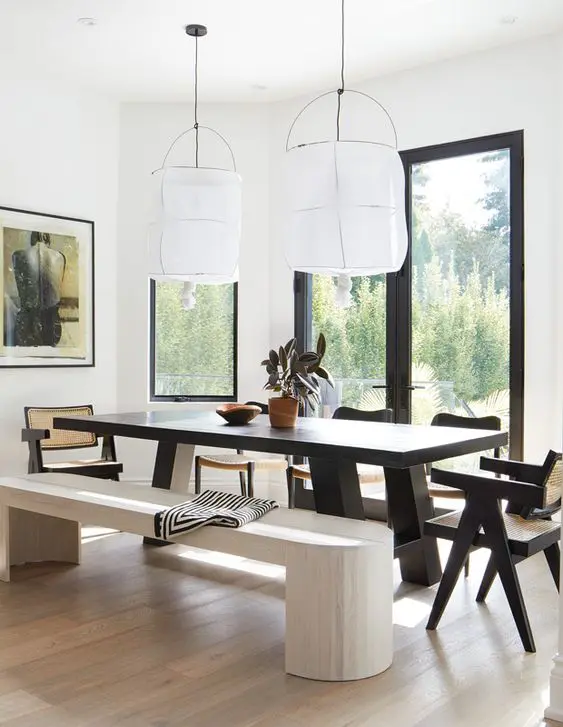 a bold dining zone with a view, a black dining table and chairs, a whitewashed bench and a light-stained floor