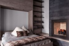 a cozy modern chalet bedroom with a floating bed, floating shelves, a fireplace and some faux fur bedding is very welcoming