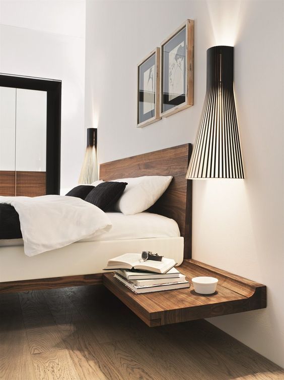 a super stylish modern bedroom with a rich-stained floating bed and matching nightstands, catchy black sconces and a duo of artworks