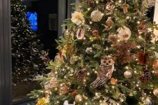 02 an oversized woodland glam Christmas tree with gold and green ornaments, pinecones, owls, vines, lights and branches plus some faux blooms