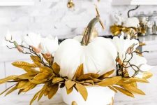 20 a glam Thanksgiving decoration of a white pumpkins, white blooms, gilded leaves on a white and gold stand is wow
