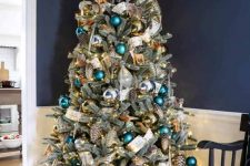 29 a pretty woodland glam Christmas tree with green, teal, gold ornaments, shiny metallic pinecones, a white printed ribbon and some deer ornaments