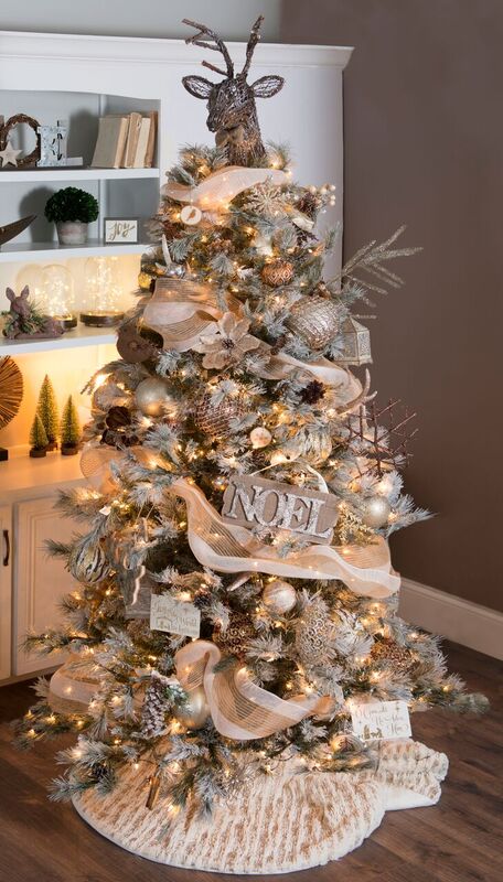 a creative woodland glam Christmas tree with lights, signs, metallic ornaments, branches, snowflakes and a deer head on top