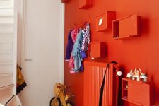 a bold red wall with matching box shelves and a radiator that create a cohesive look as they match in color and look modern