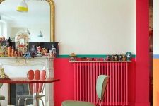 a bold vintage-inspired interior with red touches including a radiator, green stools and chairs, a faux fireplace and an oversized mirror