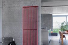 a contemporary industrial space of concrete and with concrete tiles plus a hot red radiator on the wall for a bold touch of color