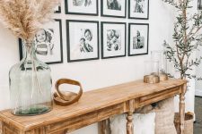 a farmhouse entryway with a vintage wooden console and a chic black and white gallery wall with white matting and black frames