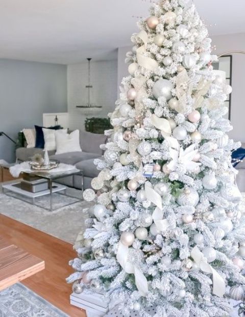 A flocked Christmas tree with pastel and metallic ornaments, white fabric ribbons and fabric blooms is a very fairy tale like idea