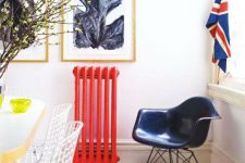 a lovely interior in neutrals with a bold red radiator, a navy chair and a pretty gallery wall is a chic space to be