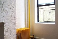 a neutral space with a cool gold-touched floor and a bold yellow vintage radiator for a bold accent in the space