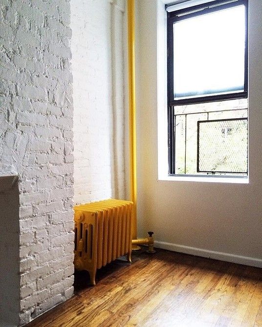 A neutral space with a cool gold touched floor and a bold yellow vintage radiator for a bold accent in the space
